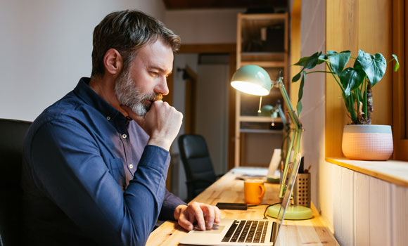 Man at his desk looking at a laptop