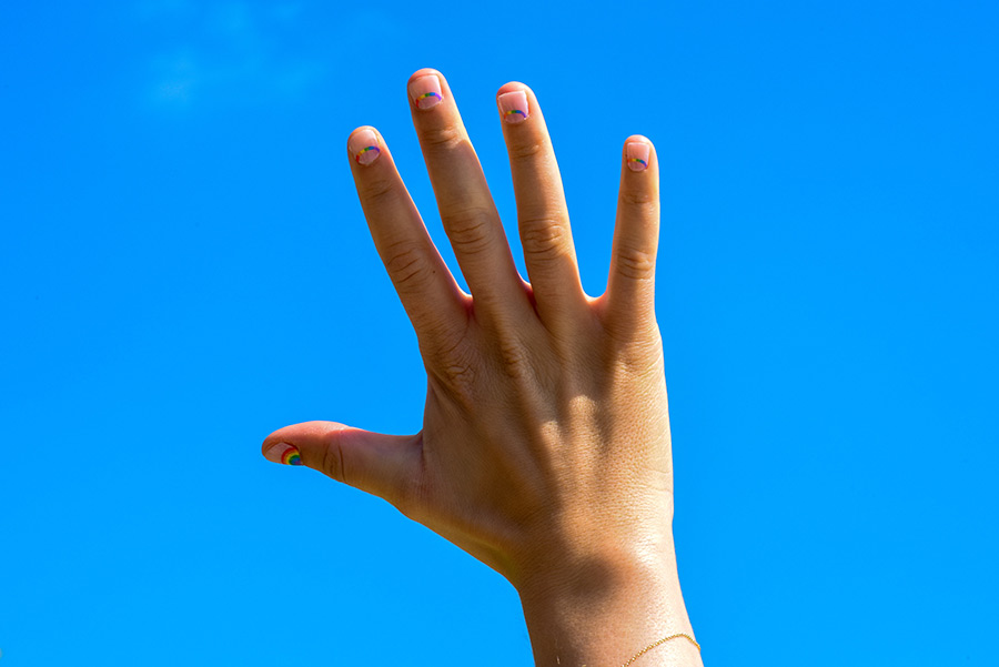person holding hand up to blue sky