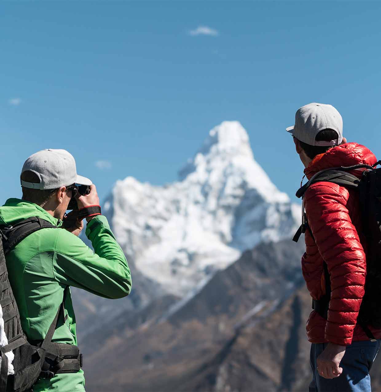 two people taking a picture of a mountain in the distance