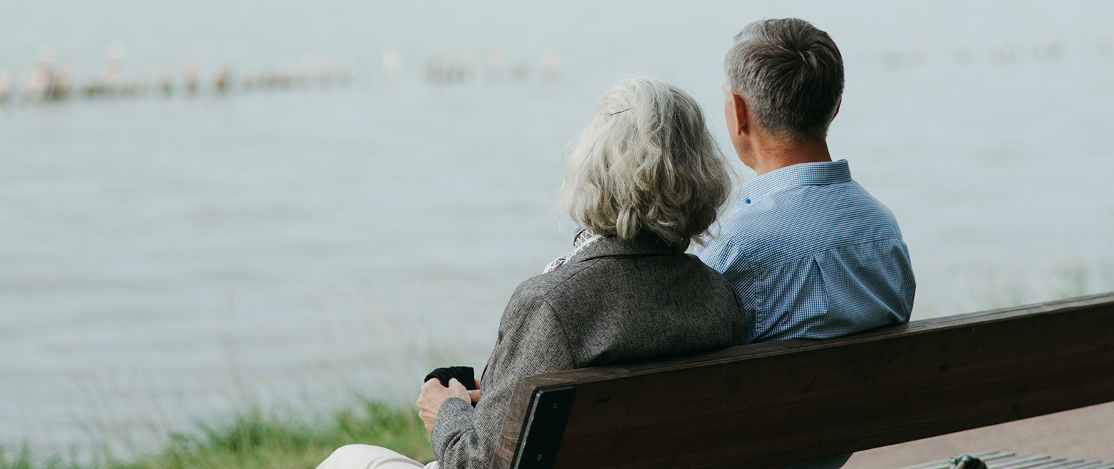 Senior couple sitting on a bench looking at a lake