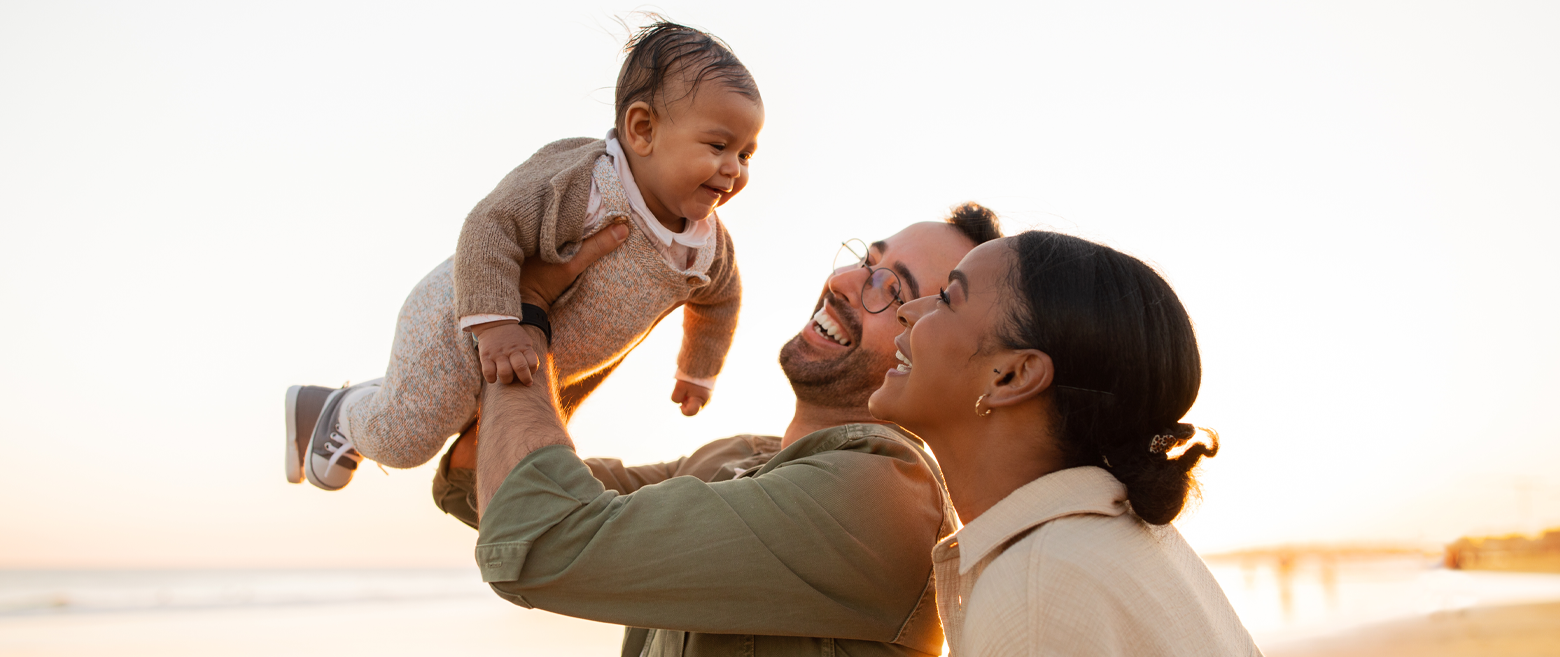 Couple holding their baby on a beach.