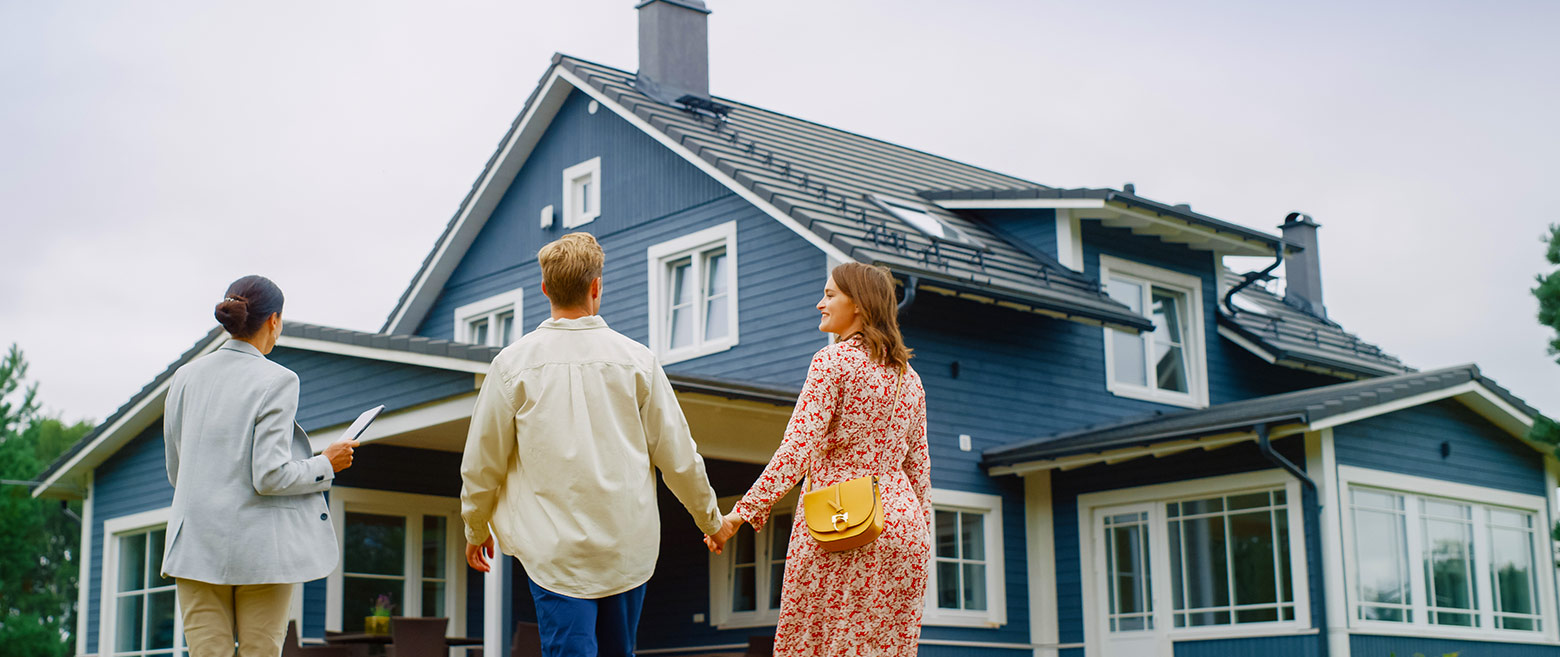 Couple standing in front oh home with an agent