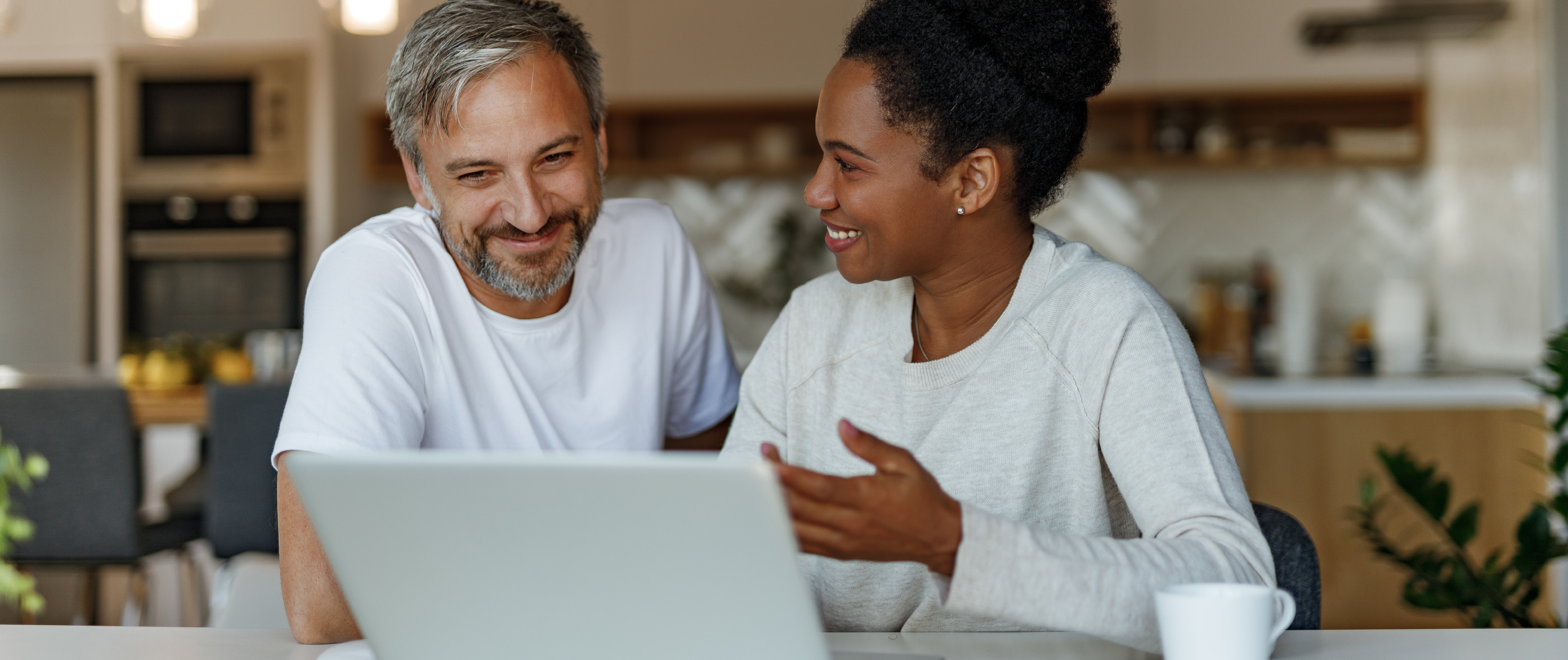 Couple smiling at each other in front of a computer. 