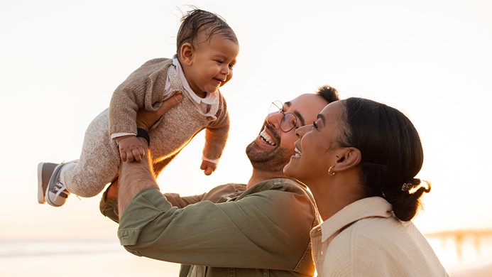 Woman and man holding baby in the air