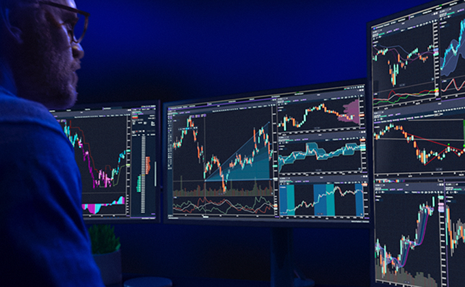 Man looking at a multi-monitor trading screen system