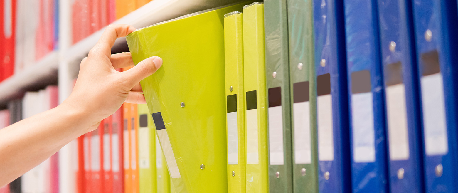 Person pulling out a binder from a shelf