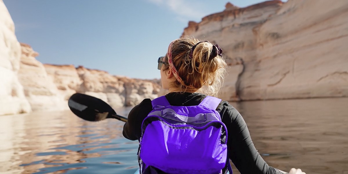 Woman kayaking on a river with a purple backpack