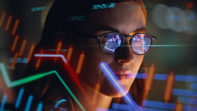 Woman looking at computer with charting around her