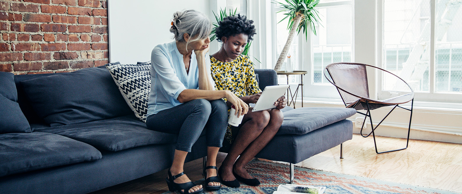 Two women looking at a computer on a couch