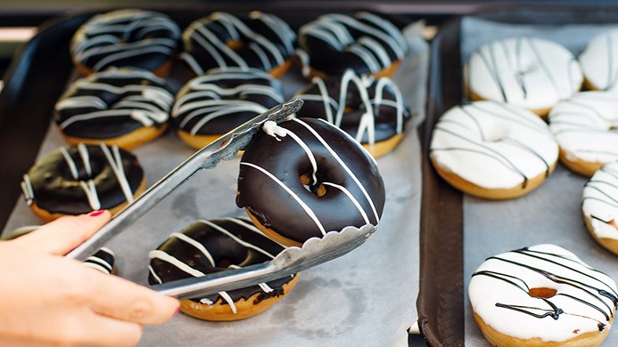 Person picking donut up with tongs