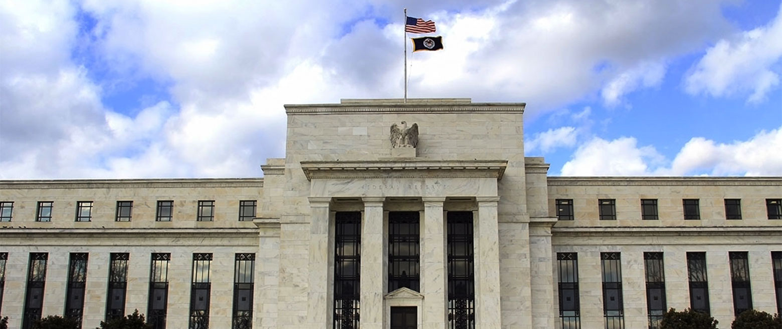 The Federal Reserve building under a partly cloudy sky.