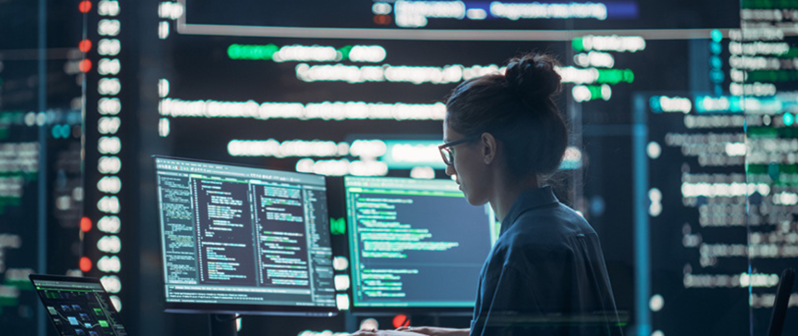 Women looking at monitors with digital screens in the background