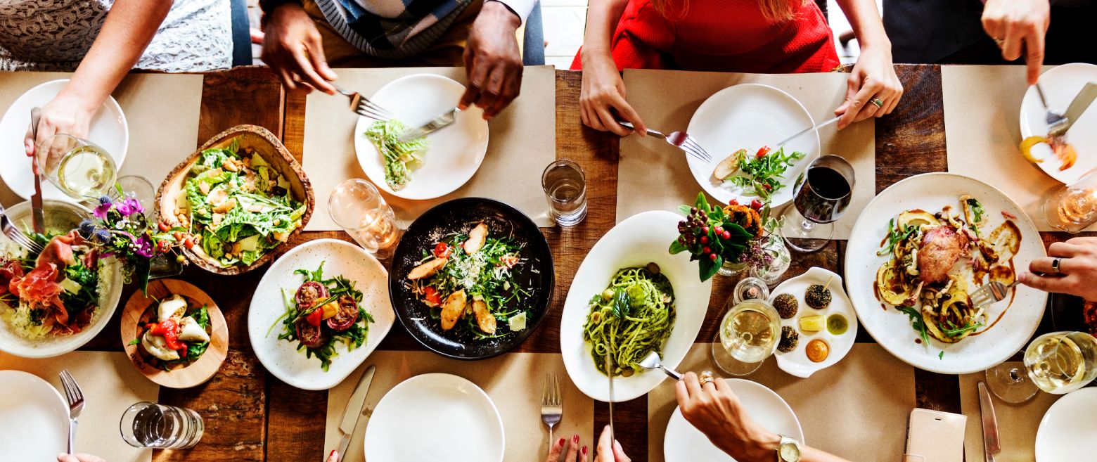 A table fool of plates and people surrounded with food on their plates. 