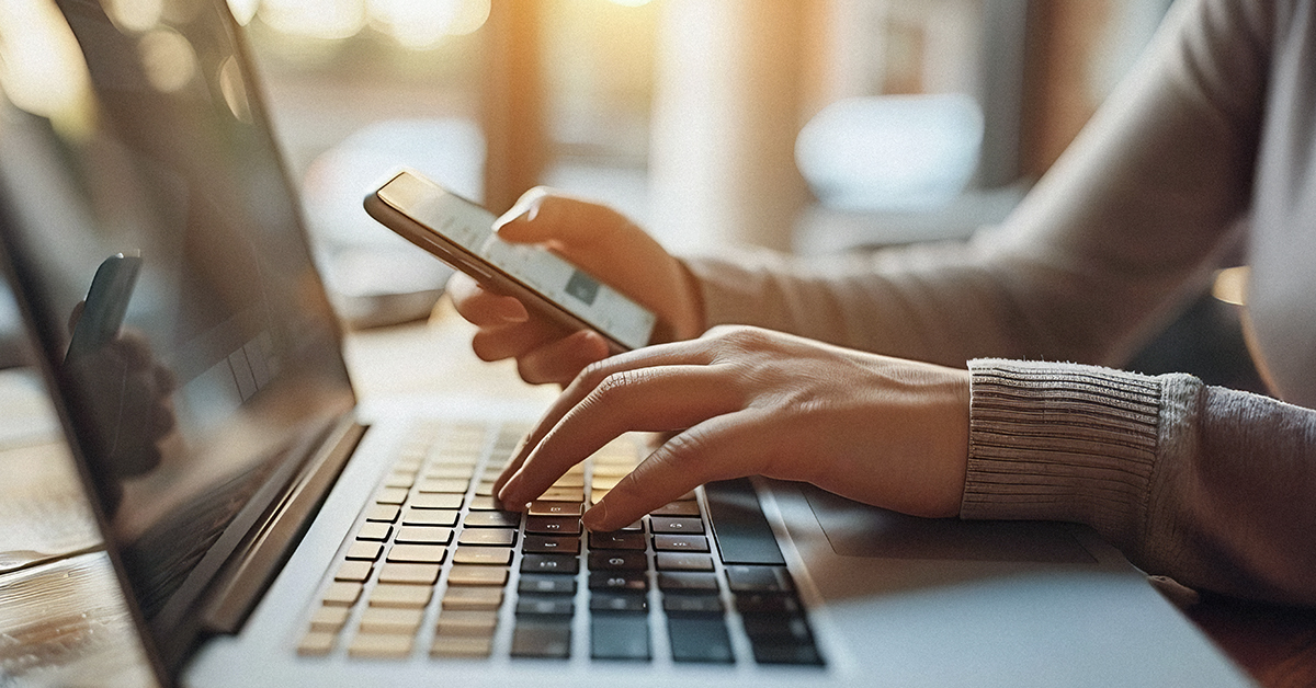 Person using a laptop and smartphone.