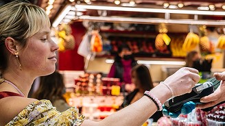 Customer making a contactless payment at a busy market stall